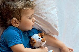 Petit garçon en train de dormir avec une peluche chien