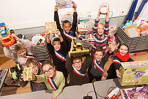 Groupe d'enfants brandissant des jouets au-dessus de leur tête