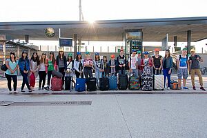 Groupe de jeunes avec leurs valises devant la gare d'Oullins