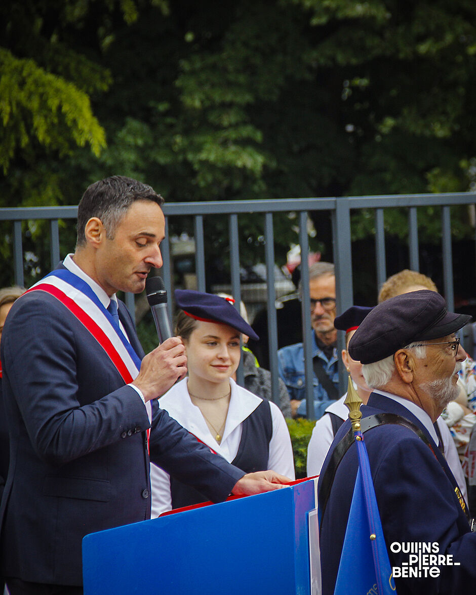 Homme brun, de profil, au micro, derrière un pupitre bleu - Agrandir l'image, .JPG 0,96Mo (fenêtre modale)